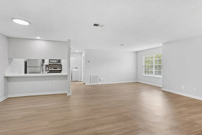 Spacious open-plan living area with modern kitchen and sleek appliances, featuring abundant natural light and stylish wooden flooring.