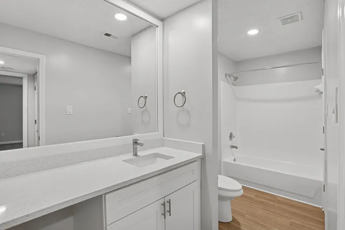 Modern bathroom with sleek white vanity, contemporary fixtures, and a spacious bathtub.