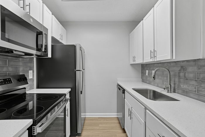 Modern kitchen with sleek stainless steel appliances, elegant white cabinetry, and a stylish backsplash, offering a contemporary and inviting atmosphere.