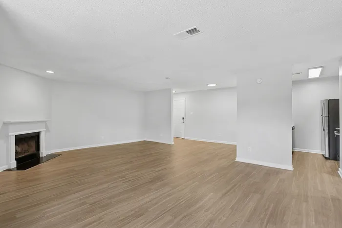 Spacious open-plan living area with elegant wood flooring and a cozy fireplace, perfect for contemporary living.