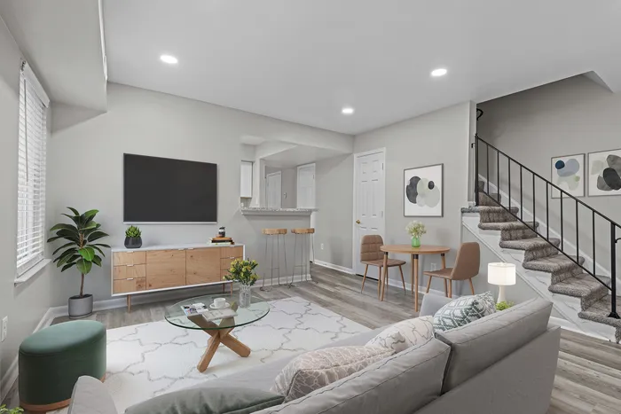 Modern open-concept living room with stylish decor, cozy seating, and elegant staircase, perfect for relaxing and entertaining.