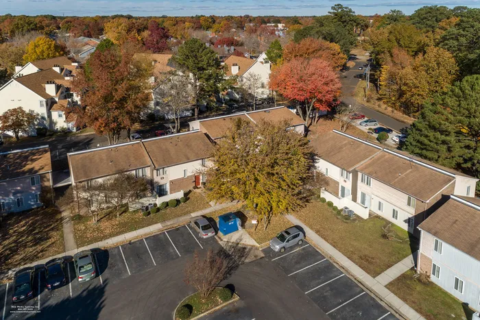 Charming townhouses nestled among vibrant autumn trees with ample parking, offering a cozy and inviting neighborhood atmosphere.