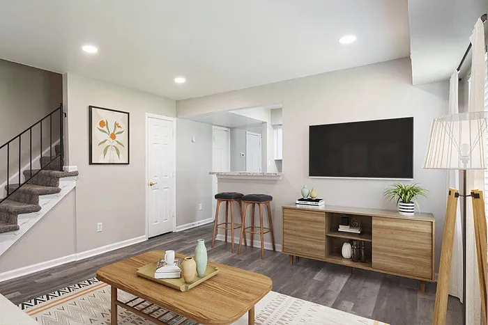 Bright and modern living room with elegant wood flooring, cozy staircase, stylish bar seating, and sleek entertainment setup.