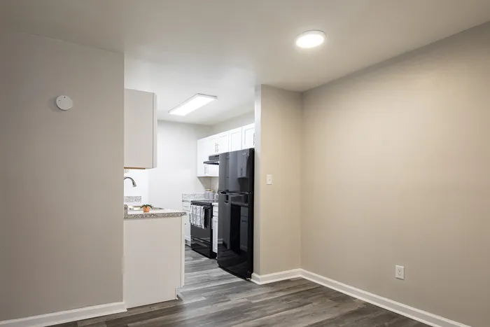 Modern apartment kitchen featuring sleek black appliances, granite countertops, and elegant wood flooring.
