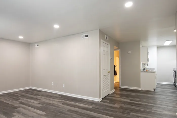 Modern apartment with elegant wood flooring, recessed lighting, and a sleek kitchen featuring granite countertops.