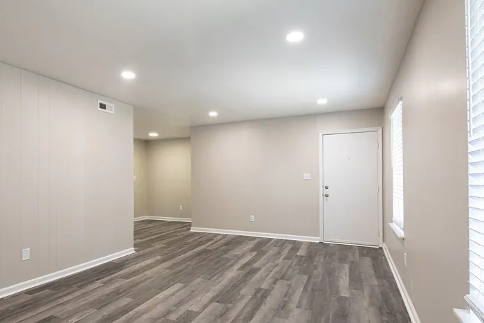 Spacious and bright living area with modern wood flooring and soft recessed lighting, offering a welcoming entrance and cozy ambiance.