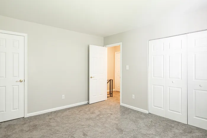 Bright and inviting bedroom with plush carpet, ample closet space, and a clean neutral palette.