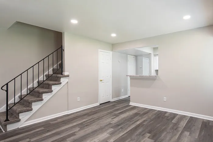 Bright and inviting interior with elegant staircase, sleek wood flooring, and an open-plan design.