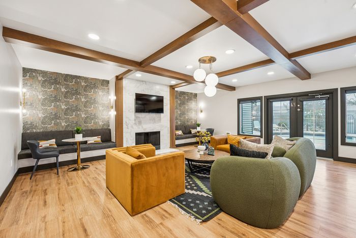 Elegant living room featuring plush seating, stylish wallpaper, and modern lighting with a view of the outdoor pool area.