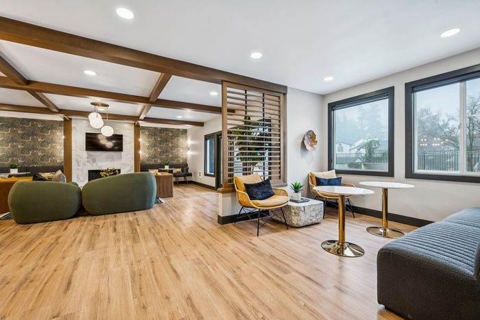Elegant, open-concept living space with modern decor, featuring a stylish seating area, wooden flooring, and large windows offering scenic views.