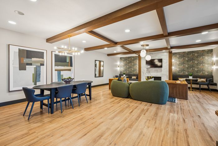 Contemporary open living space featuring a stylish dining area, cozy green sofas, and modern abstract art, ideal for entertaining.