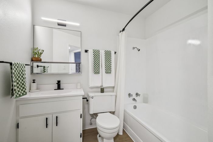 Bright, modern bathroom with sleek fixtures, white cabinetry, and stylish green accents.