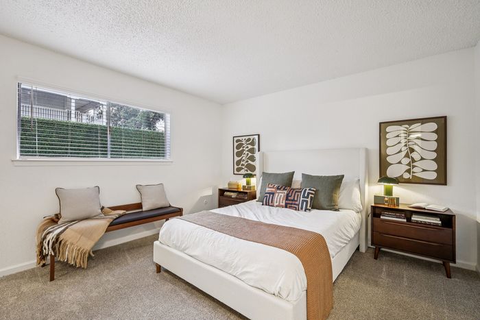 Bright and inviting bedroom with elegant decor, featuring a comfortable bed, bedside tables, and large window with natural light.