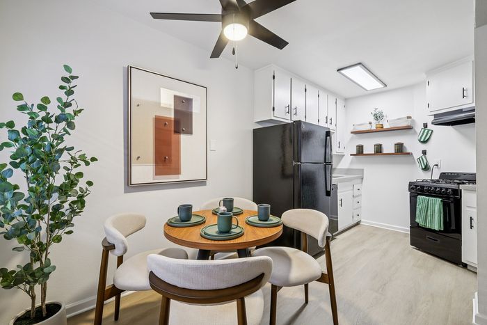 Inviting modern kitchen and dining area with sleek black appliances, elegant cabinetry, and a cozy round dining table set for four.