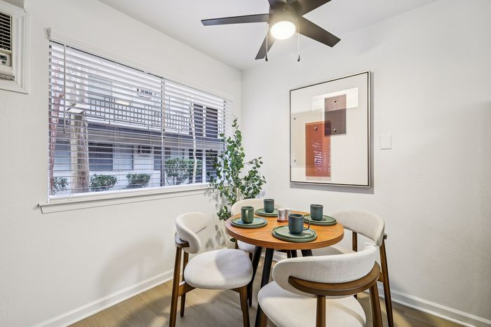 Charming dining nook with a modern round table set for four, accented by contemporary art and abundant natural light.