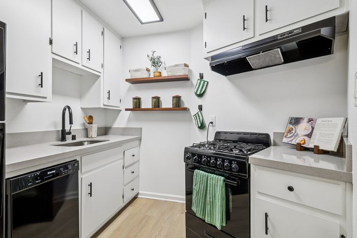 Modern kitchen design with sleek white cabinets, elegant countertops, and black appliances, creating a stylish and functional culinary space.