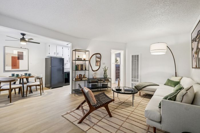 Bright and inviting living space with modern decor, featuring a cozy seating area, sleek dining set, and stylish open kitchen.