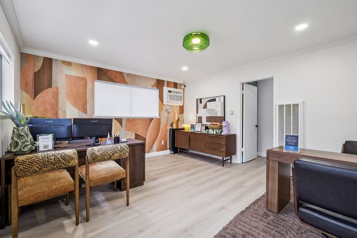 Modern office space featuring stylish wooden furniture, vibrant patterned chairs, and artistic wall decor.