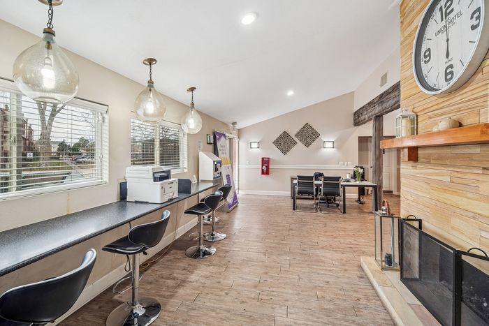 Modern communal space with sleek bar seating, pendant lighting, and a cozy fireplace ambiance.