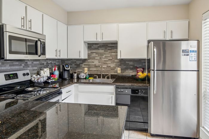 Modern kitchen with sleek stainless steel appliances, granite countertops, and stylish white cabinetry, exuding elegance and functionality.