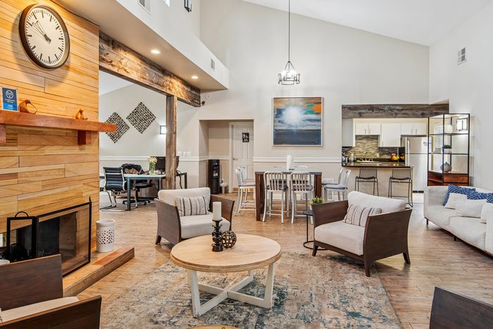 Inviting open-concept living space featuring a cozy fireplace, stylish seating area, modern kitchen, and dining setup with chic decor.
