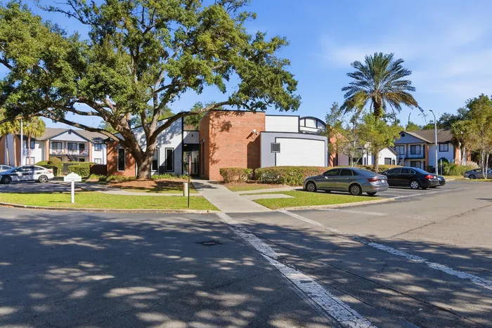 Townhomes at TSC Charming apartment complex featuring modern brick and siding architecture, surrounded by lush trees and ample parking.