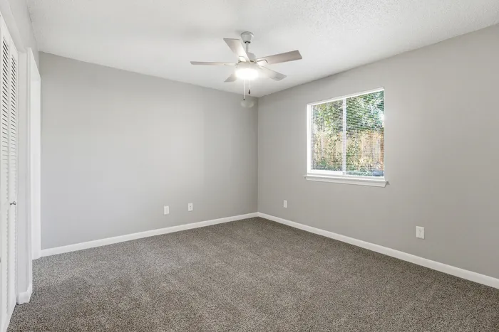 Townhomes at TSC Bright and inviting bedroom with plush carpet, neutral walls, modern ceiling fan, and ample natural light.