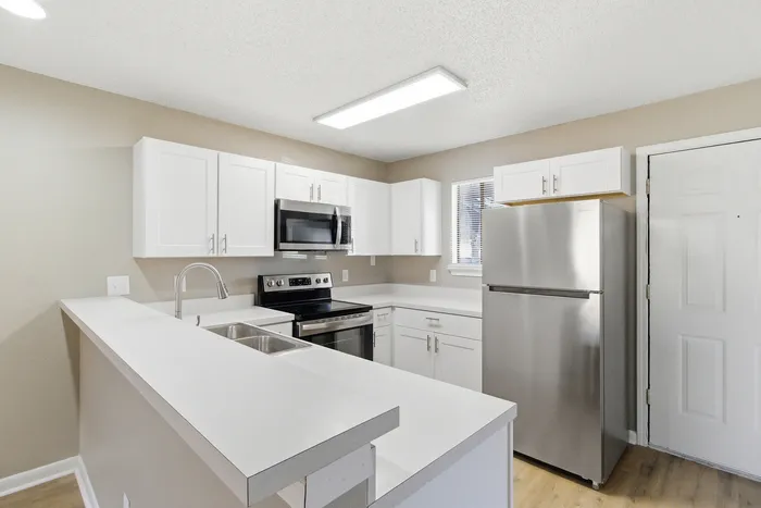 Townhomes at TSC Bright and modern kitchen with sleek stainless steel appliances, elegant white cabinets, and a spacious countertop.