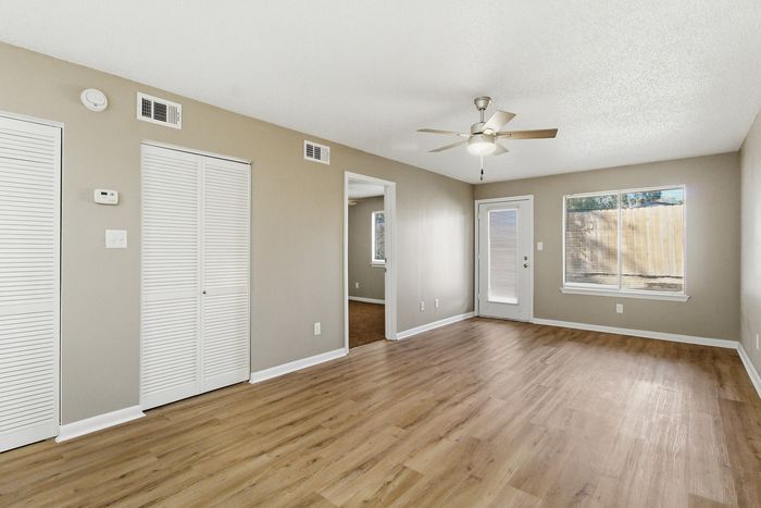Townhomes at TSC Bright and spacious living room with elegant wood flooring, large window, and modern ceiling fan. Perfect for creating a cozy and inviting home atmosphere.