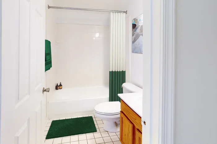 Bright and clean bathroom with classic white tiles, featuring a modern shower curtain, stylish wood cabinet, and elegant decor accents.