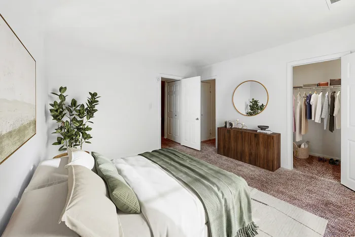 Inviting bedroom with natural lighting, plush bedding, large walk-in closet, and stylish decor, perfect for relaxation.