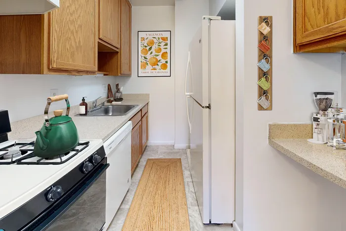 Charming kitchen with warm wooden cabinetry, modern appliances, and artistic decor in a cozy apartment.