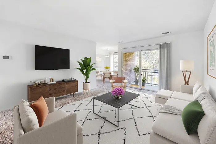Bright and modern living room with sleek furniture, a large TV, and a cozy seating area, leading to a balcony with serene views.