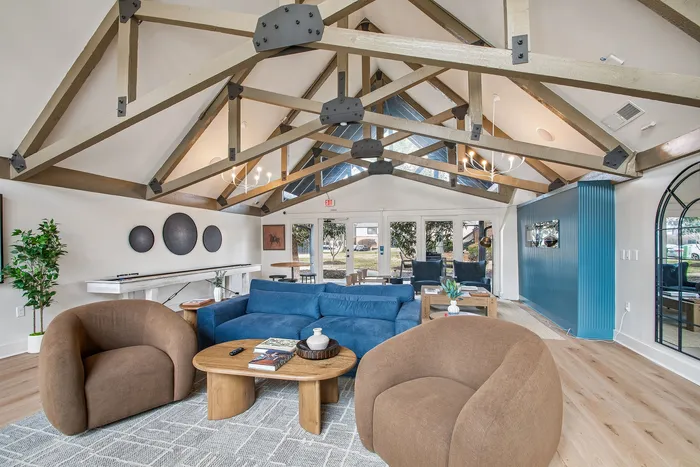Elegant living room with exposed beam ceiling, cozy seating, and a modern chandelier, offering a stylish and welcoming atmosphere.