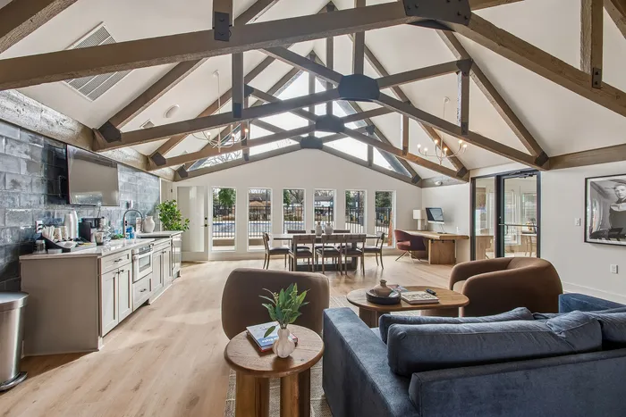Inviting open-concept living space with exposed wooden beams, modern kitchen, and elegant dining area with abundant natural light.