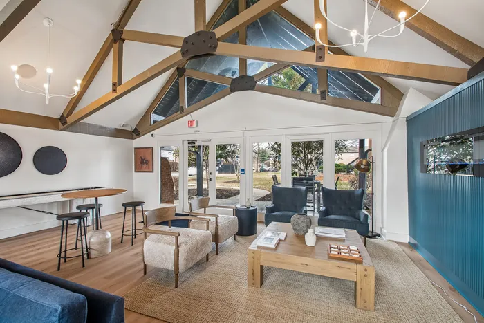 Elegant living room with vaulted ceiling, wooden beams, and chic decor, featuring plush seating and modern lighting, offering a cozy yet stylish ambiance.