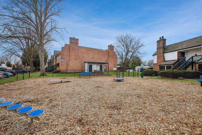 Charming outdoor playground in a cozy apartment community, offering generous open space, modern play equipment, and inviting residential buildings in the background.