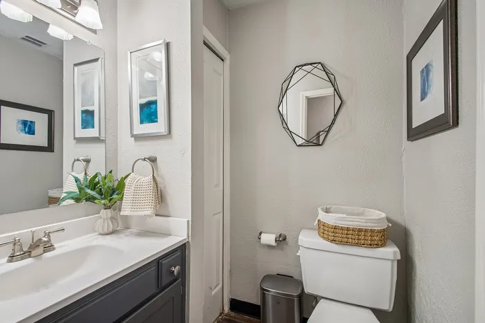 Chic and modern bathroom featuring sleek fixtures, stylish wall art, and a decorative mirror for a touch of elegance.