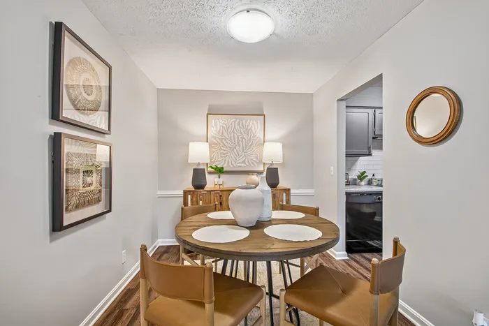 Elegant dining area with stylish wooden table and leather chairs, complemented by modern art and soft lighting in an inviting space.
