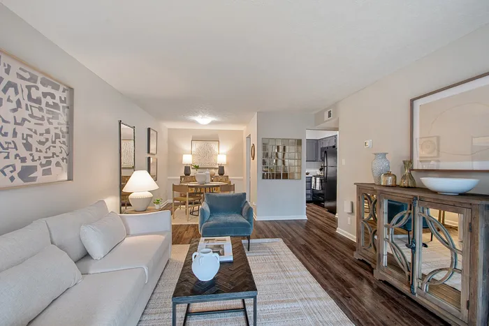 Contemporary living room with chic decor, featuring a cozy sofa, elegant lighting, and a seamless flow into a stylish dining area and modern kitchen.