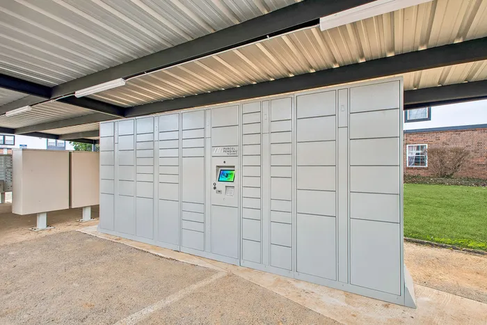 Modern parcel locker system under a sheltered area, offering secure and convenient package storage for residents.