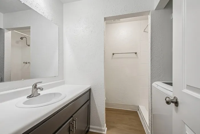 Modern bathroom with elegant white countertop, stylish faucet, and inviting walk-in shower.