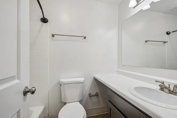 Bright and modern bathroom with sleek white fixtures, elegant countertop, and ample mirror space for a refreshing start to your day.