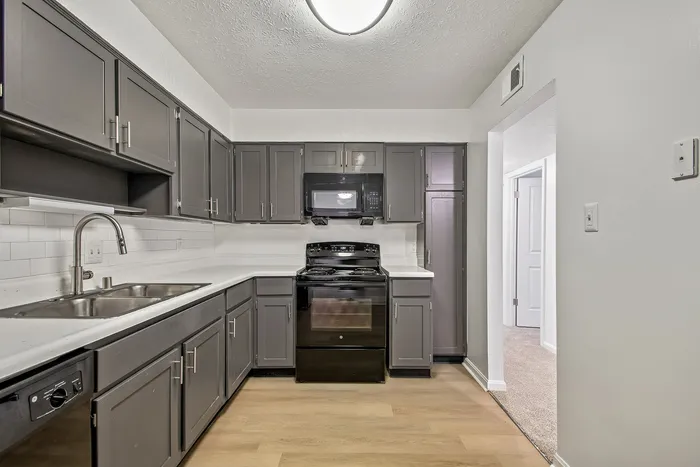 Modern kitchen with sleek grey cabinets, tile backsplash, and contemporary appliances.