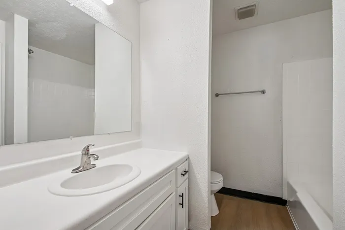 Bright modern bathroom with sleek white cabinetry, large mirror, and elegant chrome fixtures.
