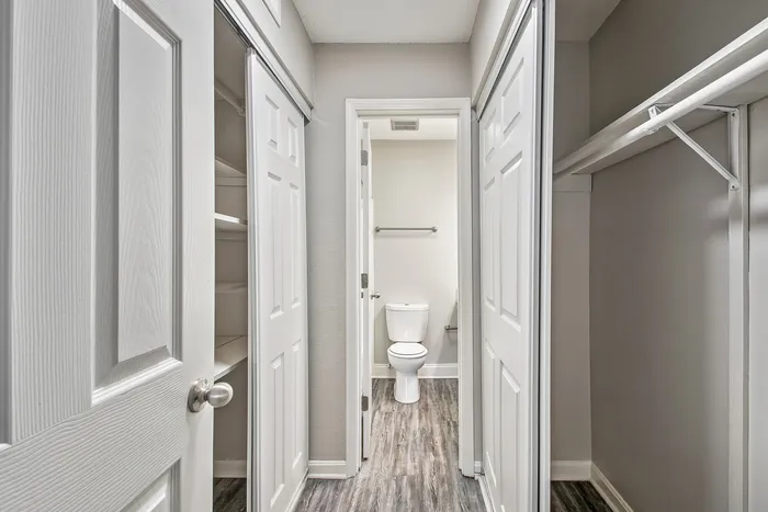 Inviting hallway view with modern sliding closet doors and access to a pristine bathroom, featuring elegant wood flooring.