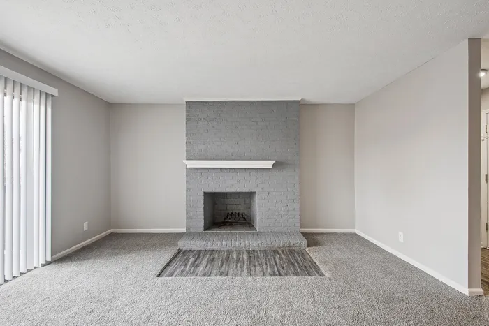 Modern living room with a stylish gray brick fireplace and plush carpet, providing a cozy and inviting atmosphere.