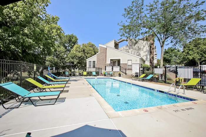 Inviting outdoor pool area surrounded by colorful lounge chairs, lush trees, and modern architecture, perfect for relaxation and enjoyment.