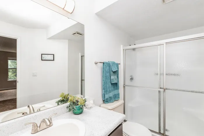 Bright and inviting bathroom featuring a modern vanity with sleek fixtures, a glass-enclosed shower, and charming decor accents.