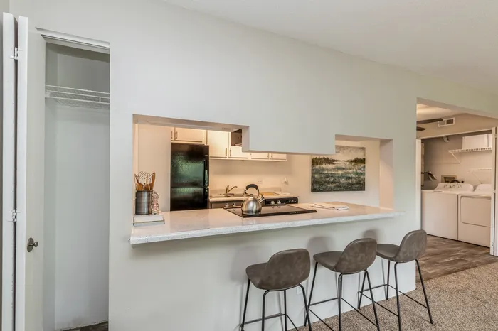 Inviting open-plan kitchen with modern bar seating, elegant countertops, and cozy adjacent laundry area.